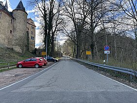 schlechte Straße, die einen Berg hinauf führt, am Rand Gebäude einer Burg