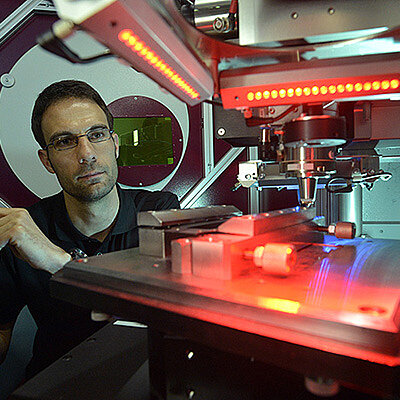 Ein Mitarbeiter bearbeitet Material mit einem Laser.