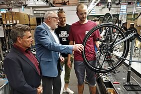 4 Männer schauen sich ein Fahrrad in der Produktion an.