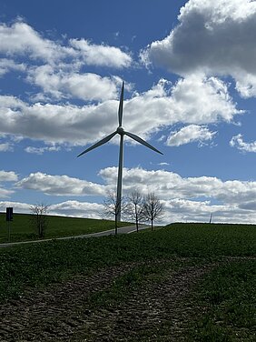 Ein Windrad auf einem Feld, im Hintergrund blauer Himmel