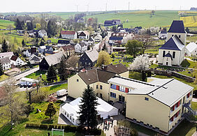 Luftaufnahme vom Dorfzentrum mit Kirche und Schule