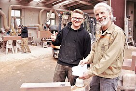 Zwei Männer stehen in einer Werkstatt