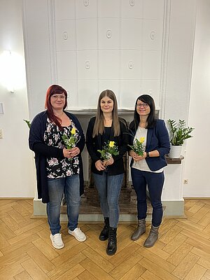 Drei Frauen mit Blumensträußen in der Hand