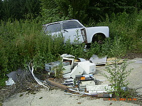 Auto und Müll in der Landschaft entsorgt