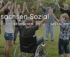 Screenshot einer Website mit einem Foto, auf dem sich Erwachsene und Kinder, Rollstuhlfahrer und farbige Menschen lachend in einem Kreis an den Händen fassen - Aufschrift Mittelsachsen Sozial
