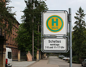 Haltestellenschild mit Zusatzzeichen "Schulbus" an einer Straße